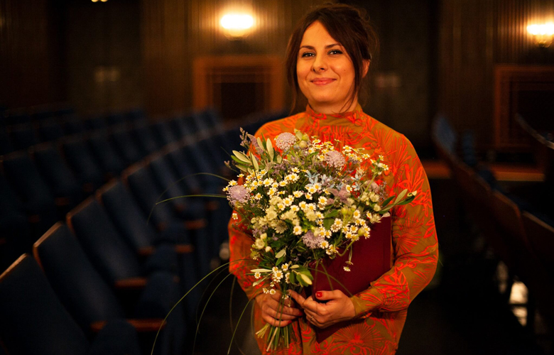 Alexandra Makarová – Preisträgerin des 4. Drehbuchwettbewerbs – in einem Kinosaal mit einen Blumenstrauß.